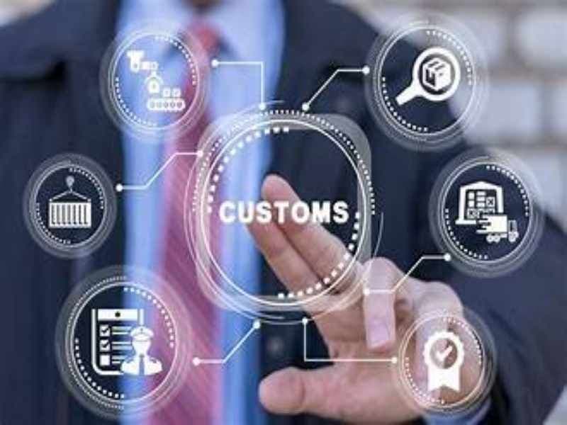 Customs Clearance Completed 2025 status showing an open cargo container at a port being inspected by customs officers for international shipping.